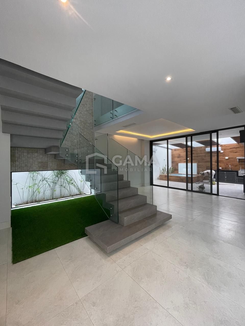 Interior con escalera de vidrio y jardín, casa en venta en Machala